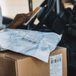 A delivery driver inside a truck with a cardboard box and a plastic mailer.