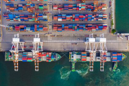 Aerial view of cargo ships being loaded with shipping containers at a busy port.
