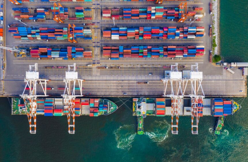 Aerial view of cargo ships being loaded with shipping containers at a busy port.