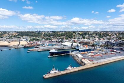 Aerial view of a coastal port with a large Strait Link cargo ship docked.