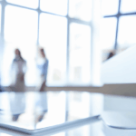 A blurred office background with a modern white desk in the foreground.