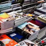 Many stacks of colorful magazines and design journals arranged on a display table.