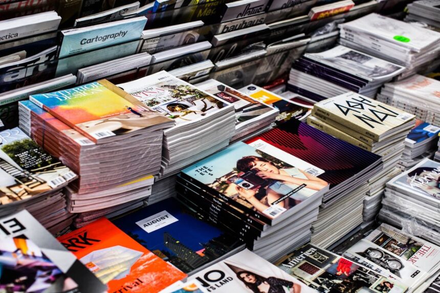 Many stacks of colorful magazines and design journals arranged on a display table.