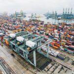 Aerial view of a busy shipping terminal filled with colorful containers and gantry cranes.