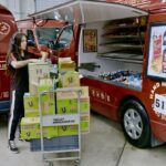 A worker loading boxes into a Tasty Fresh Food Co. catering van.
