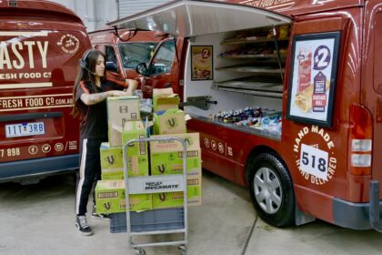 A worker loading boxes into a Tasty Fresh Food Co. catering van.