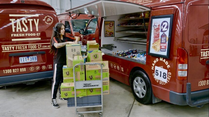 A worker loading boxes into a Tasty Fresh Food Co. catering van.