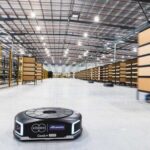 Autonomous mobile robots transporting shelves in a modern automated warehouse.