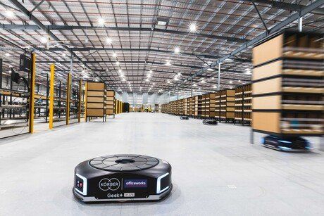 Autonomous mobile robots transporting shelves in a modern automated warehouse.