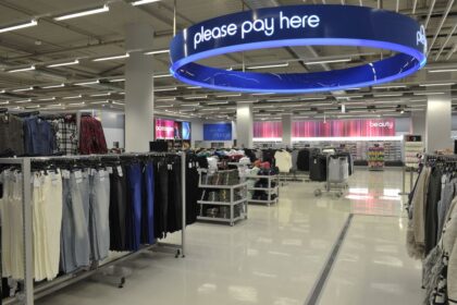 Interior of a retail store with a large blue please pay here sign overhead.