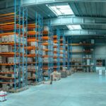 Modern industrial warehouse featuring rows of high metal shelving stacked with cardboard boxes.