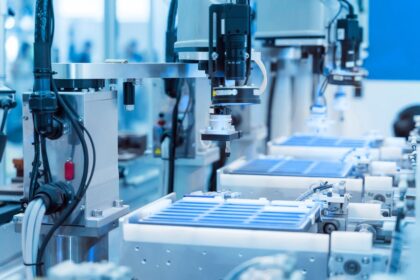 Automated industrial robotic arm assembly line with blue components on a conveyor.
