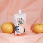 A pouch of Bae Juice Korean pear juice surrounded by three fresh pears.