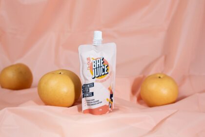A pouch of Bae Juice Korean pear juice surrounded by three fresh pears.