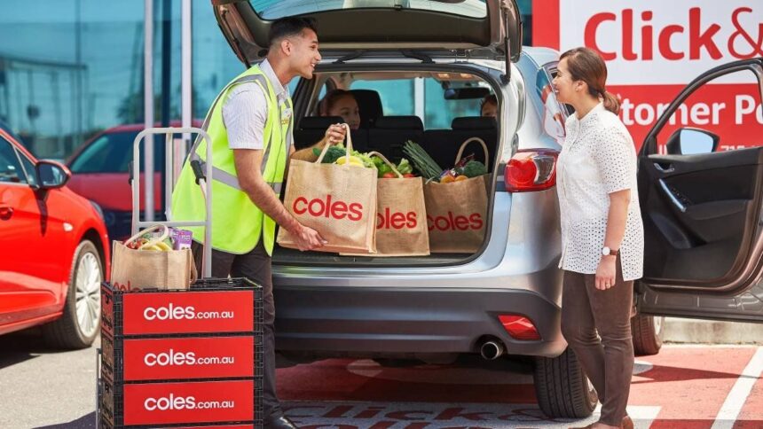 A Coles staff member loads groceries into the trunk of a customer's car.
