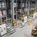 High-angle view of a warehouse with storage racks and moving forklifts.