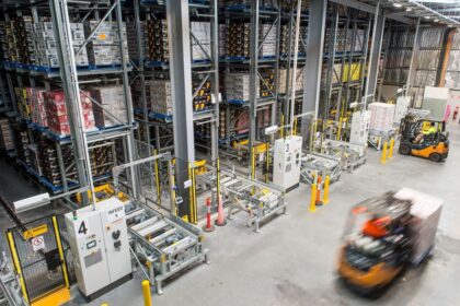 High-angle view of a warehouse with storage racks and moving forklifts.
