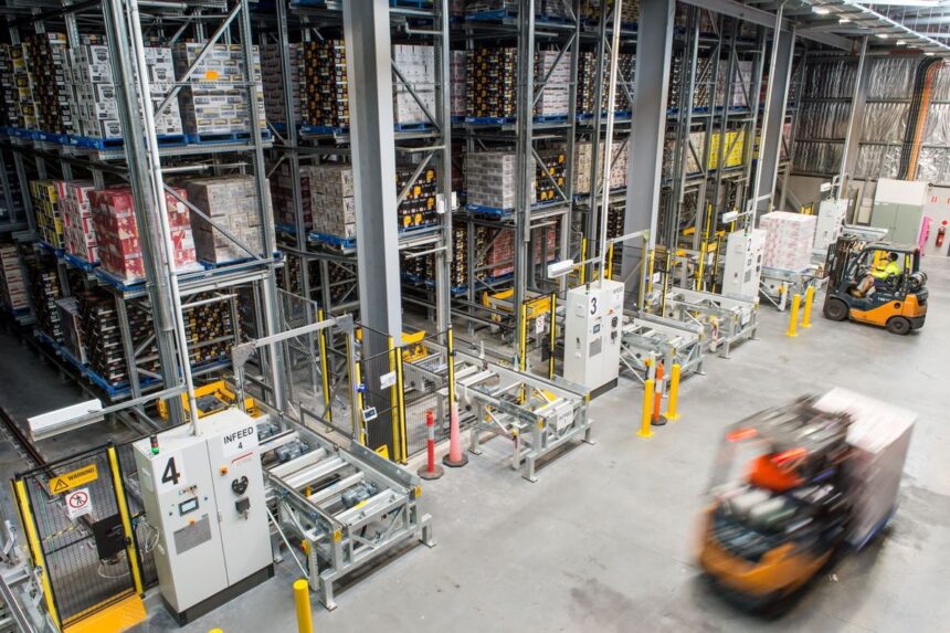 High-angle view of a warehouse with storage racks and moving forklifts.