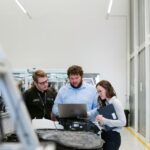 Three people working on a project in a high-tech manufacturing workshop.