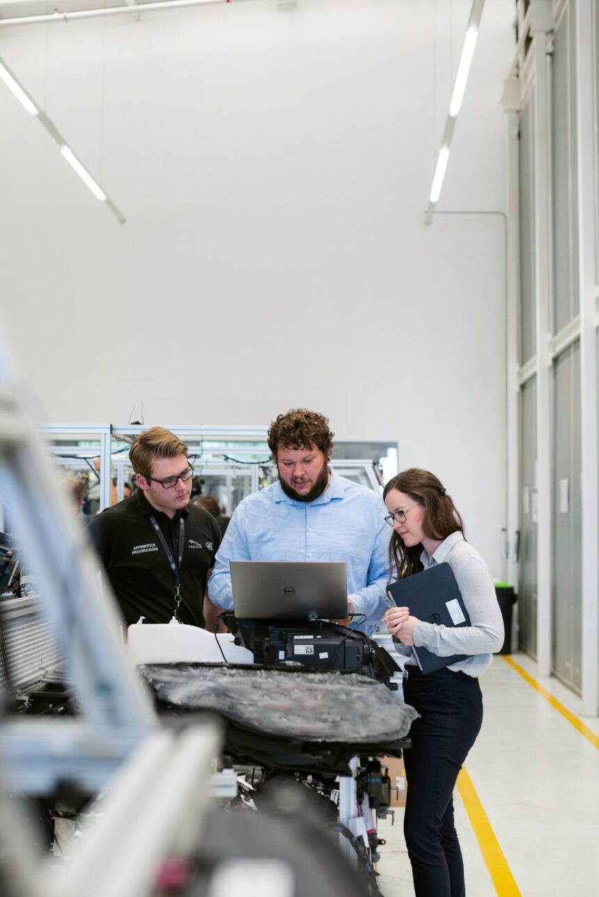 Three people working on a project in a high-tech manufacturing workshop.