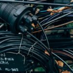 Close-up of a black fiber optic splice closure connected to coiled cables.