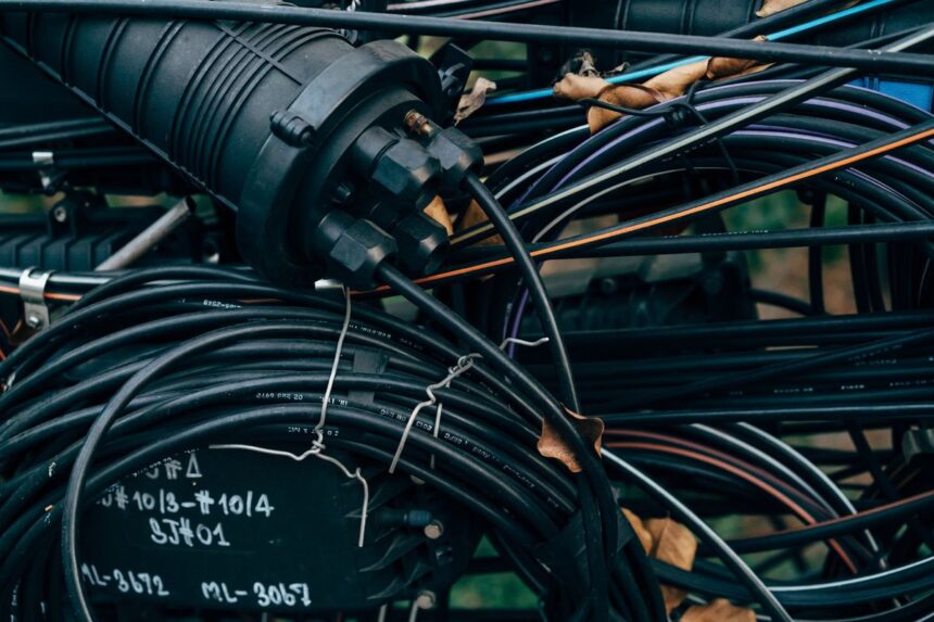 Close-up of a black fiber optic splice closure connected to coiled cables.