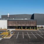 Modern industrial building with parking lot under clear blue sky.