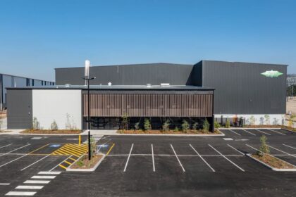 Modern industrial building with parking lot under clear blue sky.