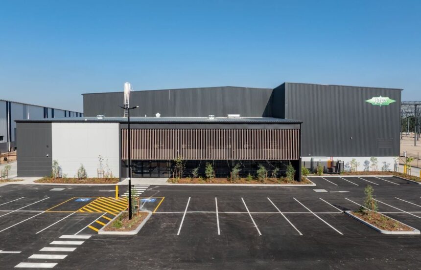 Modern industrial building with parking lot under clear blue sky.