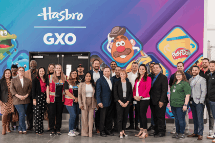 A large, diverse group of professional people posing in front of a Hasbro mural.