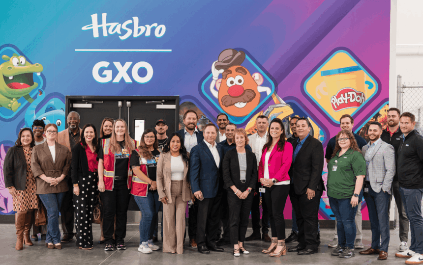 A large, diverse group of professional people posing in front of a Hasbro mural.