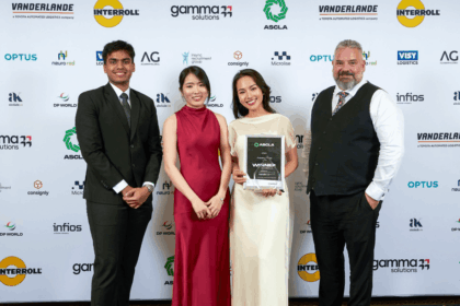 Four people stand in front of a branded backdrop for an award presentation ceremony.
