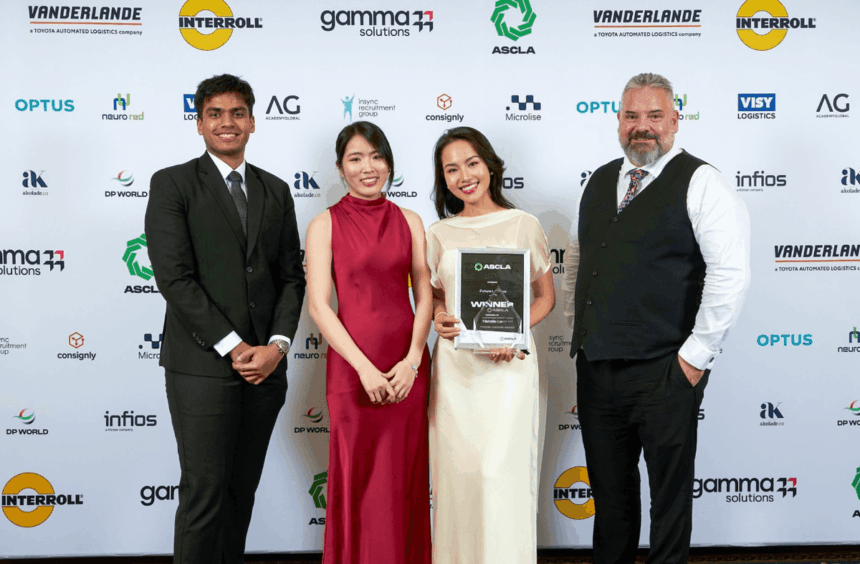 Four people stand in front of a branded backdrop for an award presentation ceremony.