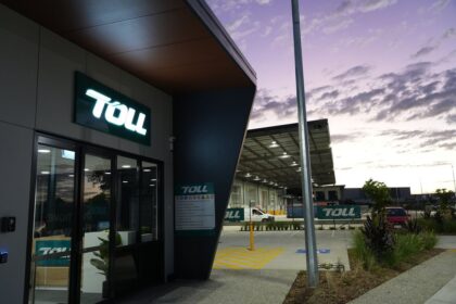 Modern Toll logistics facility entrance at dusk with a purple sunset sky.