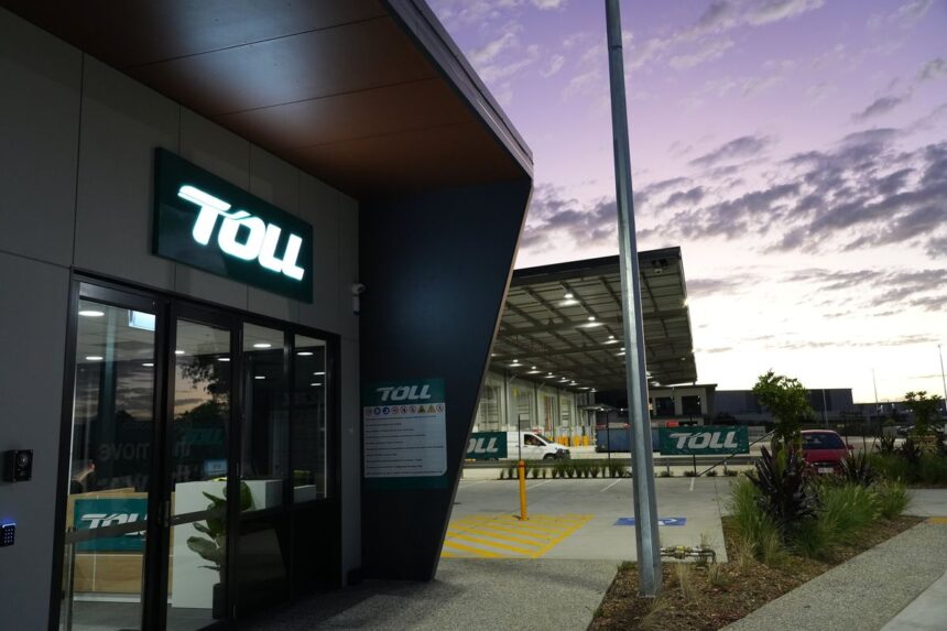 Modern Toll logistics facility entrance at dusk with a purple sunset sky.