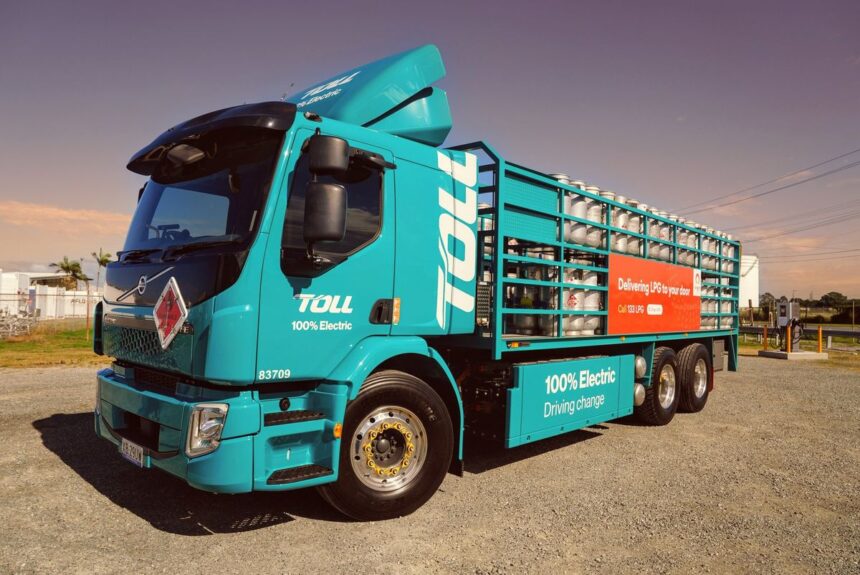 A turquoise Toll 100% electric truck carrying LPG cylinders parked outdoors.