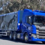 A blue Scania truck with a Colorbond-branded trailer parked on a road.