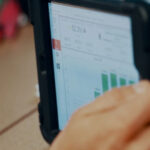 Close-up of a tablet showing manufacturing performance data and charts, representing Argon & Co’s partnership with QAD Redzone.
