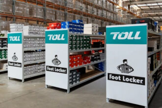 Toll and Foot Locker branded warehouse shelving filled with footwear stock, highlighting their extended ANZ logistics partnership.