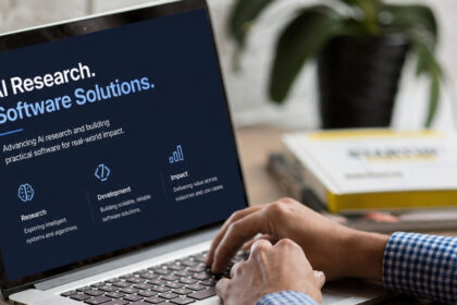 Laptop screen showing AI research and software solutions messaging, with a person working beside a coffee cup and notebook.