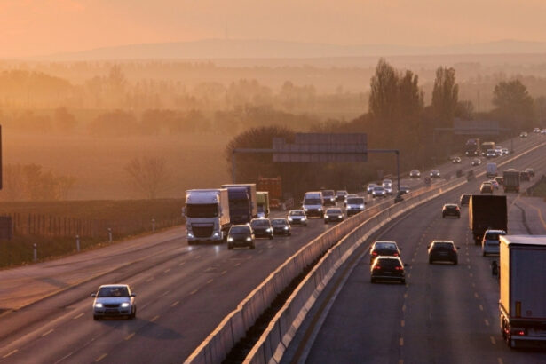 Alt text: Trucks and cars travelling along a highway at sunrise, representing transport, logistics and mobile infrastructure pressures.