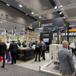 Visitors gather at the Dematic stand during CeMAT Australia 2026, where live demonstrations of warehouse automation technologies, including AutoStore and a 4-way pallet shuttle system, attract attendees exploring intelligent supply chain solutions. Large Dematic branding and exhibition displays are visible throughout the busy trade show floor.