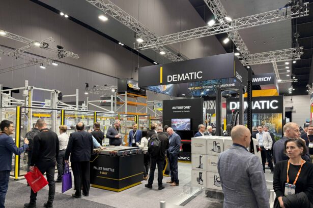 Visitors gather at the Dematic stand during CeMAT Australia 2026, where live demonstrations of warehouse automation technologies, including AutoStore and a 4-way pallet shuttle system, attract attendees exploring intelligent supply chain solutions. Large Dematic branding and exhibition displays are visible throughout the busy trade show floor.