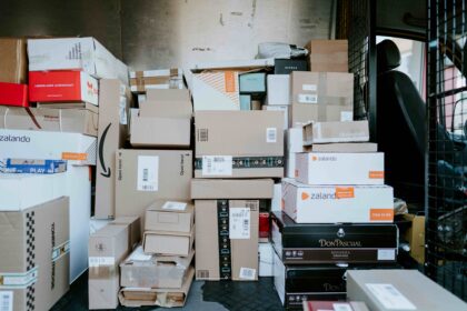 The cargo area of a delivery van is filled with stacked cardboard parcels and retail shipping boxes of various sizes, ready for transport and last-mile delivery.