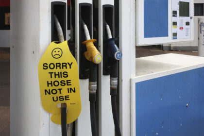 Close-up of a petrol station fuel pump with three fuel nozzles. A bright yellow cover on one nozzle displays a sad face icon and the words, "SORRY THIS HOSE NOT IN USE," indicating the pump is out of service.