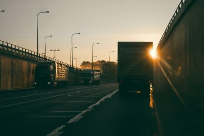 A delivery truck drives down a highway with the sunset ahead.