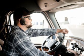 A man is driving a truck wearing a hands-free headset.