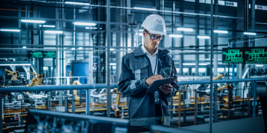 A man uses handheld device while standing in a warehouse environment.