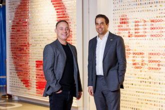 Two men in suits stand in front of the Australia Post logo.