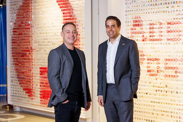 Two men in suits stand in front of the Australia Post logo.